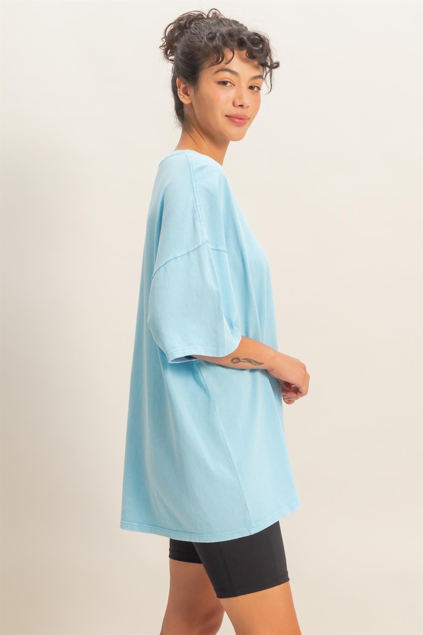 woman wearing a relaxed fit light blue oversized t-shirt with short sleeves and black bike shorts