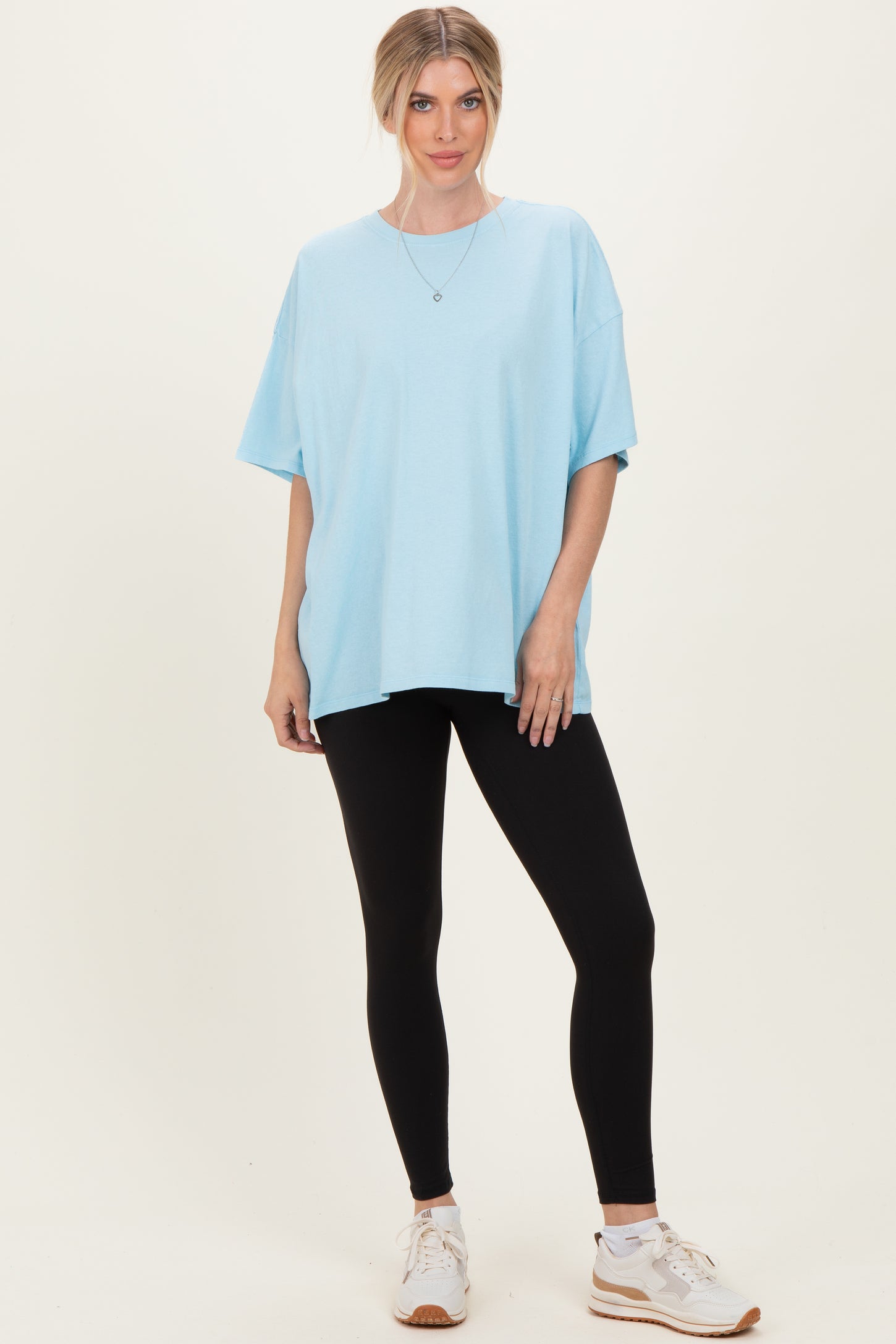 woman wearing a light blue oversized t-shirt and black leggings with white athletic shoes