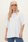 woman wearing an oversized white t-shirt with short sleeves and blue jeans, paired with a beige cap