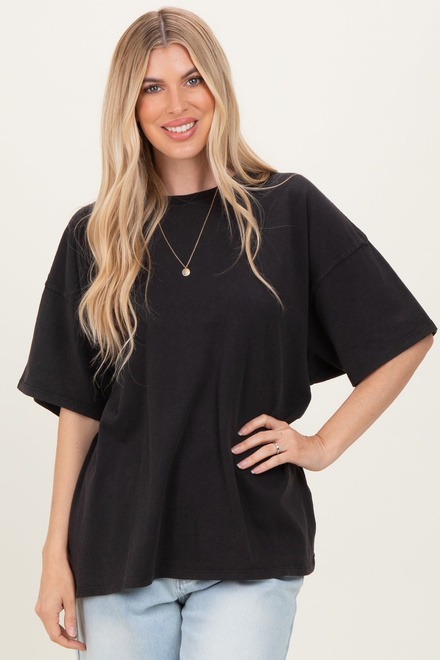 woman wearing a black oversized t-shirt with loose sleeves and styled with light blue jeans