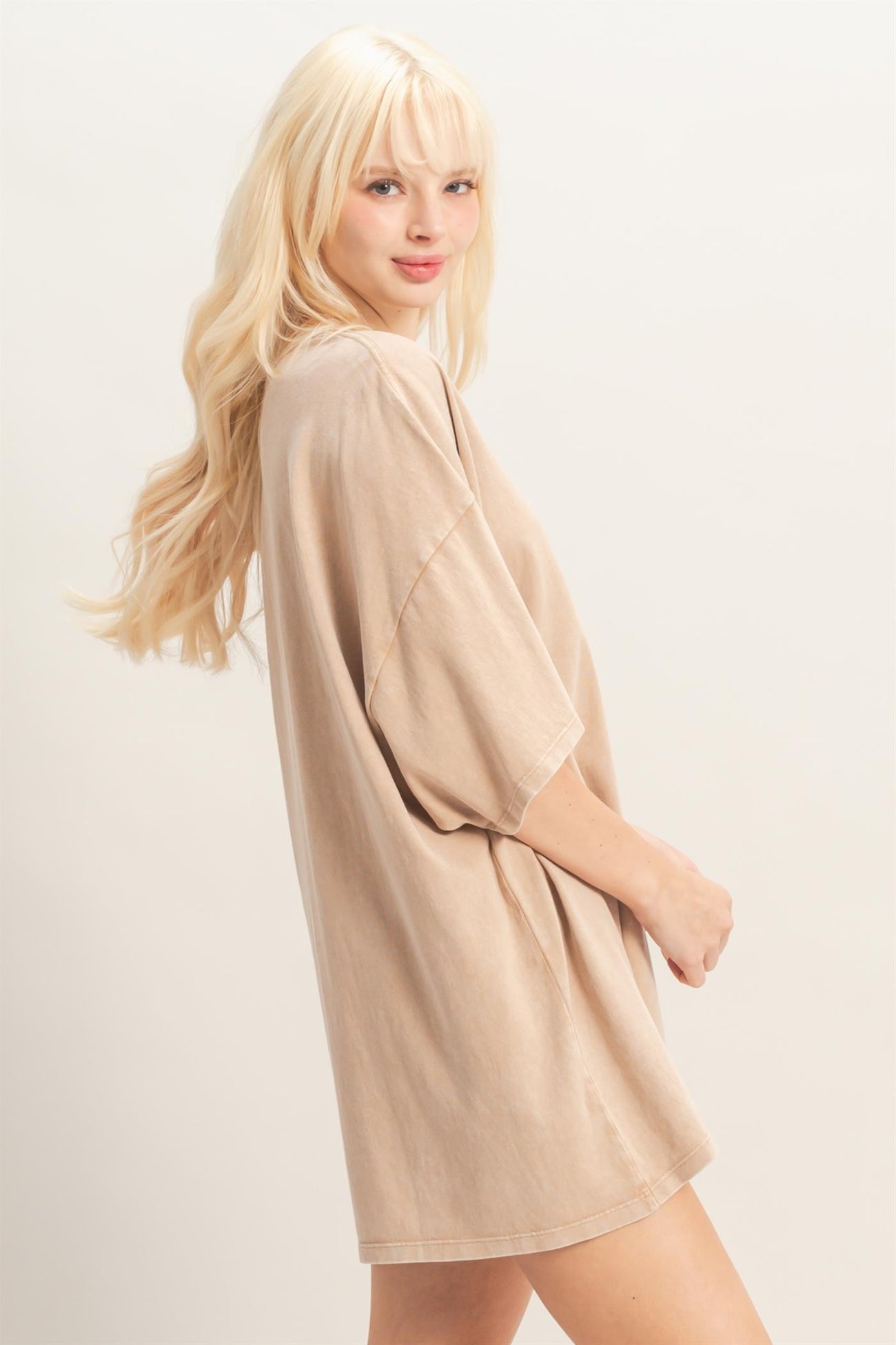 woman wearing a beige oversized t-shirt dress with short sleeves and a relaxed fit