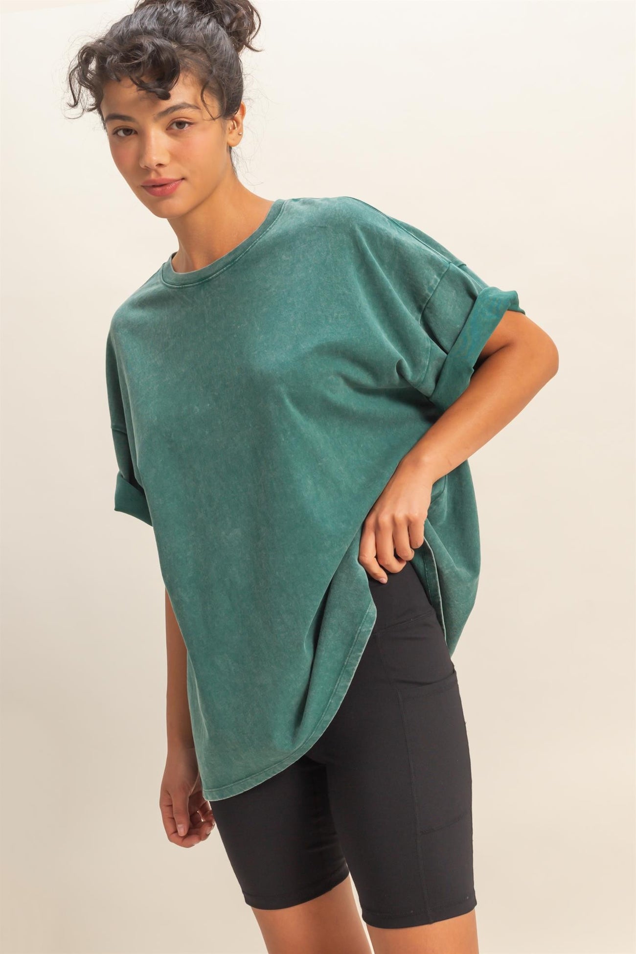 woman wearing a green oversized crew neck t-shirt with rolled sleeves and black bike shorts