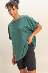 woman wearing a green oversized crew neck t-shirt with rolled sleeves and black bike shorts