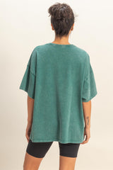 woman wearing an oversized green vintage-style t-shirt and black bike shorts, seen from the back