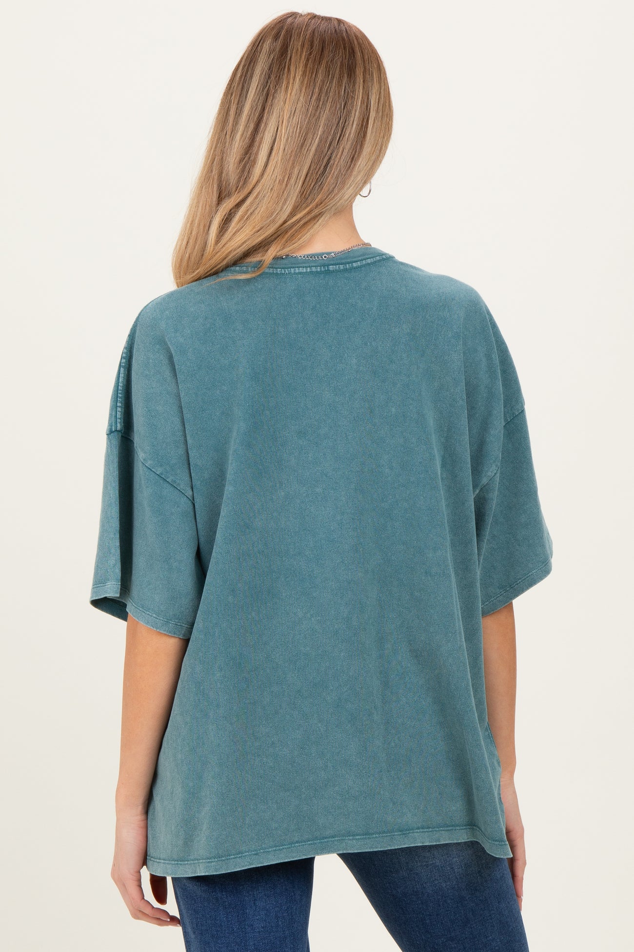 woman wearing a loose-fitting faded teal maternity top with short sleeves and a relaxed fit from the back