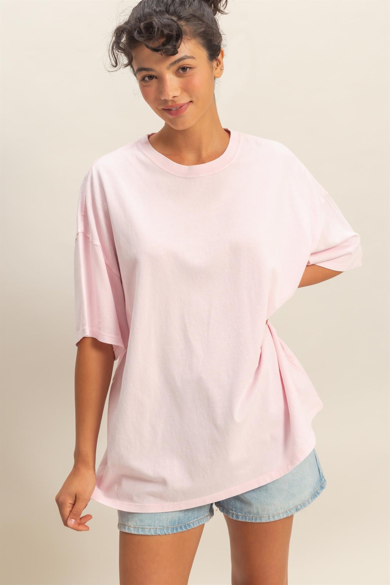 woman wearing a light pink oversized t-shirt with short sleeves and casual denim shorts