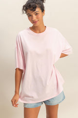 woman wearing a light pink oversized t-shirt with short sleeves and casual denim shorts