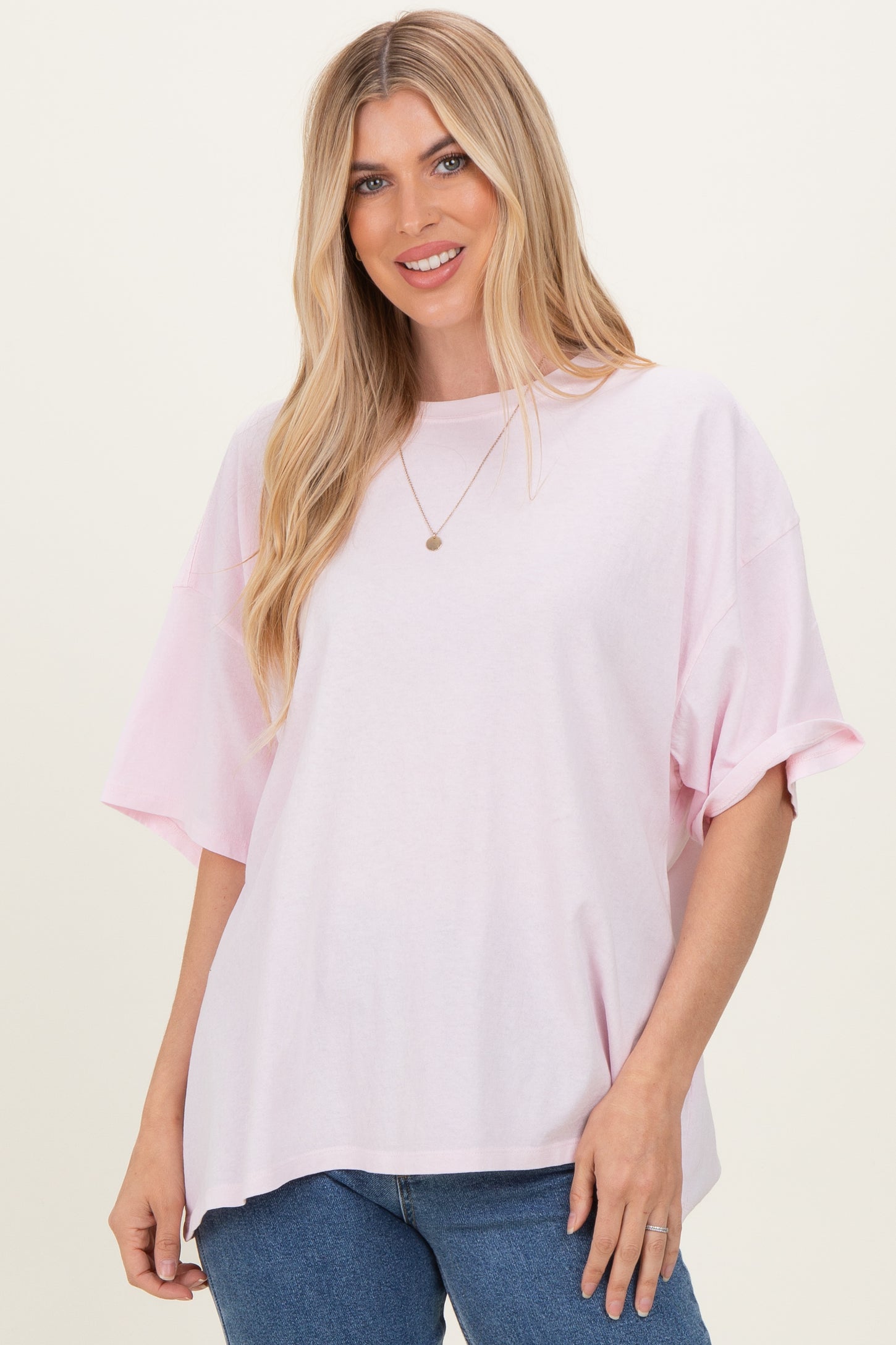 woman wearing a light pink oversized t-shirt with short sleeves and a relaxed fit