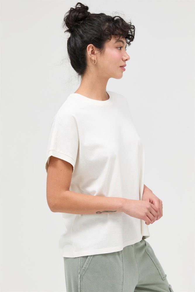 woman wearing a cream short sleeve t-shirt with relaxed fit and styled hair, paired with green pants