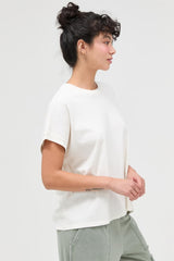 woman wearing a cream short sleeve t-shirt with relaxed fit and styled hair, paired with green pants