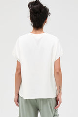 woman wearing a loose-fitting white t-shirt with rolled sleeves and a rounded hem, viewed from the back