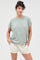 woman wearing a relaxed fit green short sleeve top with rolled sleeves and cream drawstring shorts