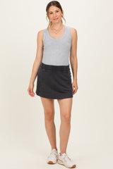 woman wearing a gray tank top and a dark gray maternity mini skirt, standing with a relaxed pose