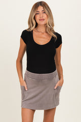 woman wearing a black scoop neck fitted top and a gray maternity skirt with pockets