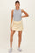 woman wearing a gray sleeveless maternity top with a yellow maternity skirt and white sneakers, showing her baby bump