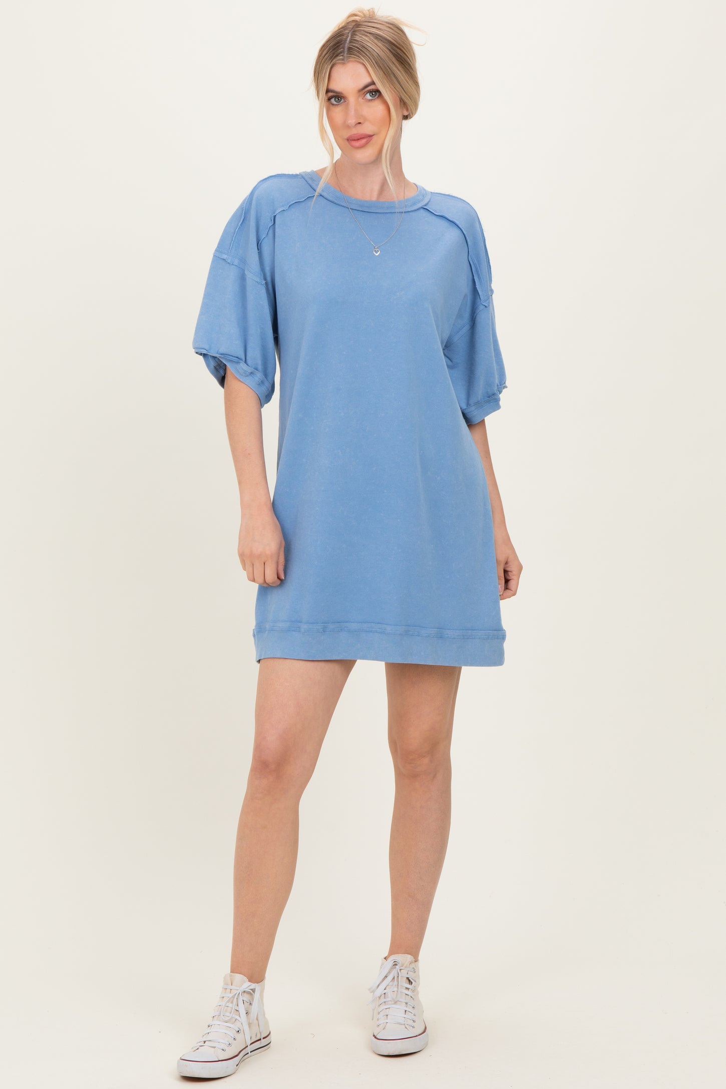 woman wearing a light blue oversized sweatshirt dress with puff sleeves and white sneakers
