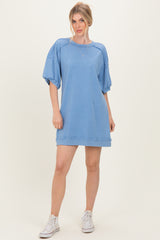woman wearing a light blue oversized sweatshirt dress with puff sleeves and white sneakers