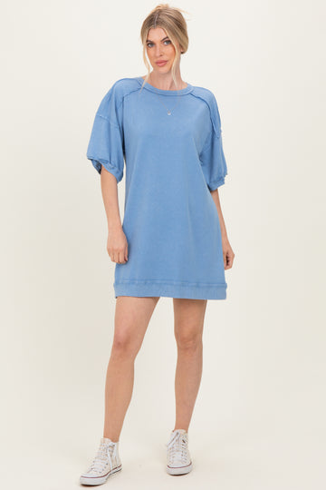 woman wearing a light blue oversized sweatshirt dress with puff sleeves and white sneakers