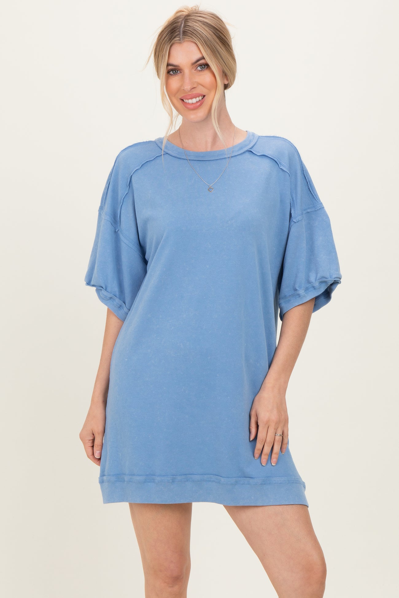 woman wearing a light blue oversized sweatshirt dress with short puff sleeves and a relaxed fit