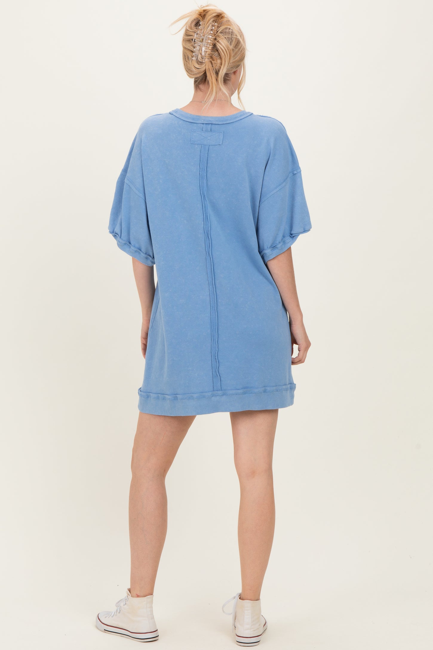 woman wearing a light blue oversized sweatshirt dress with short sleeves and a relaxed fit