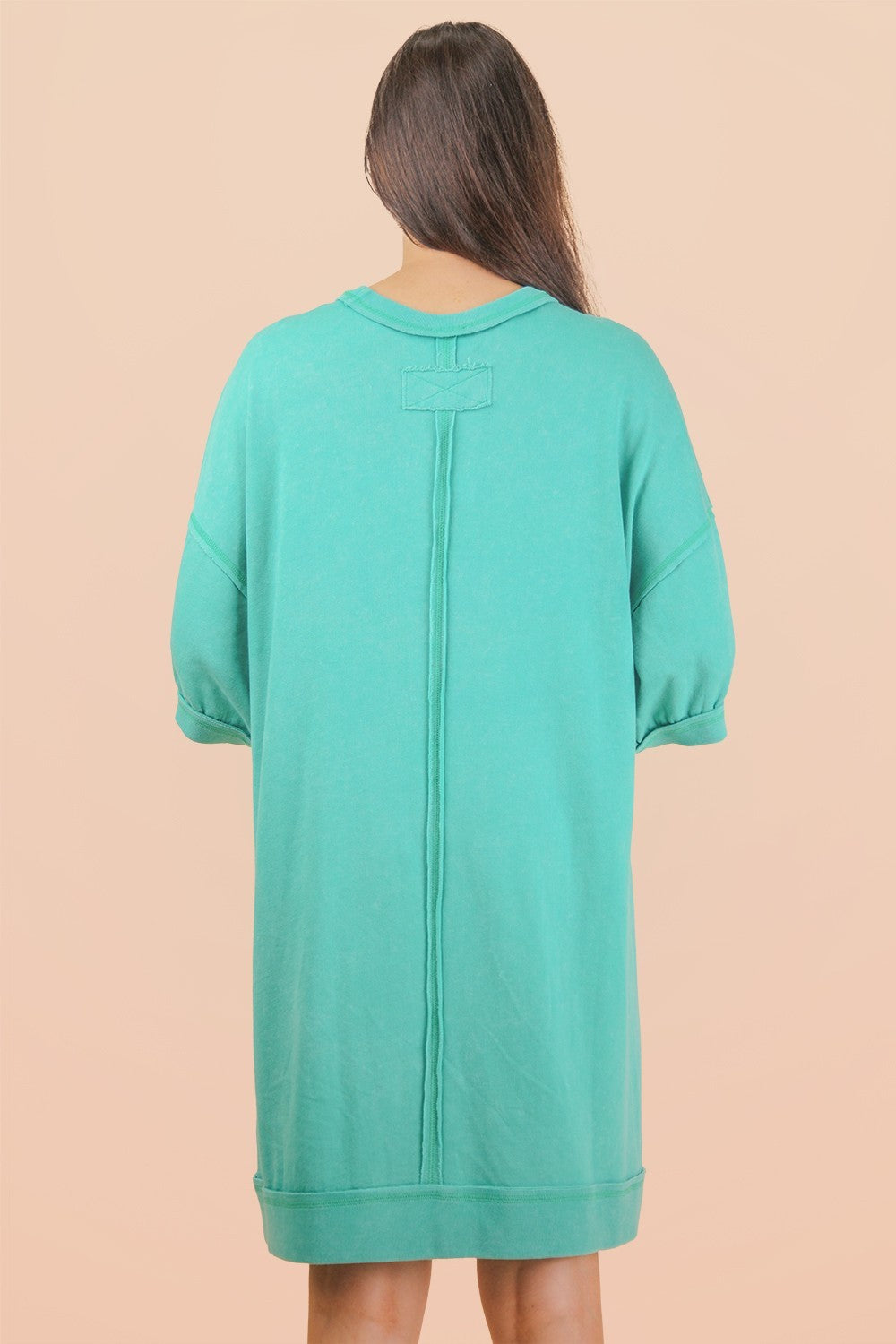 woman wearing a mint green oversized sweatshirt dress with short sleeves and back seam detail