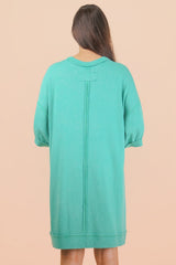 woman wearing a mint green oversized sweatshirt dress with short sleeves and back seam detail
