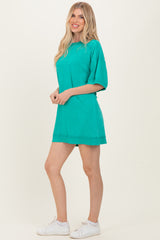 woman wearing a teal oversized short sleeve dress paired with white sneakers