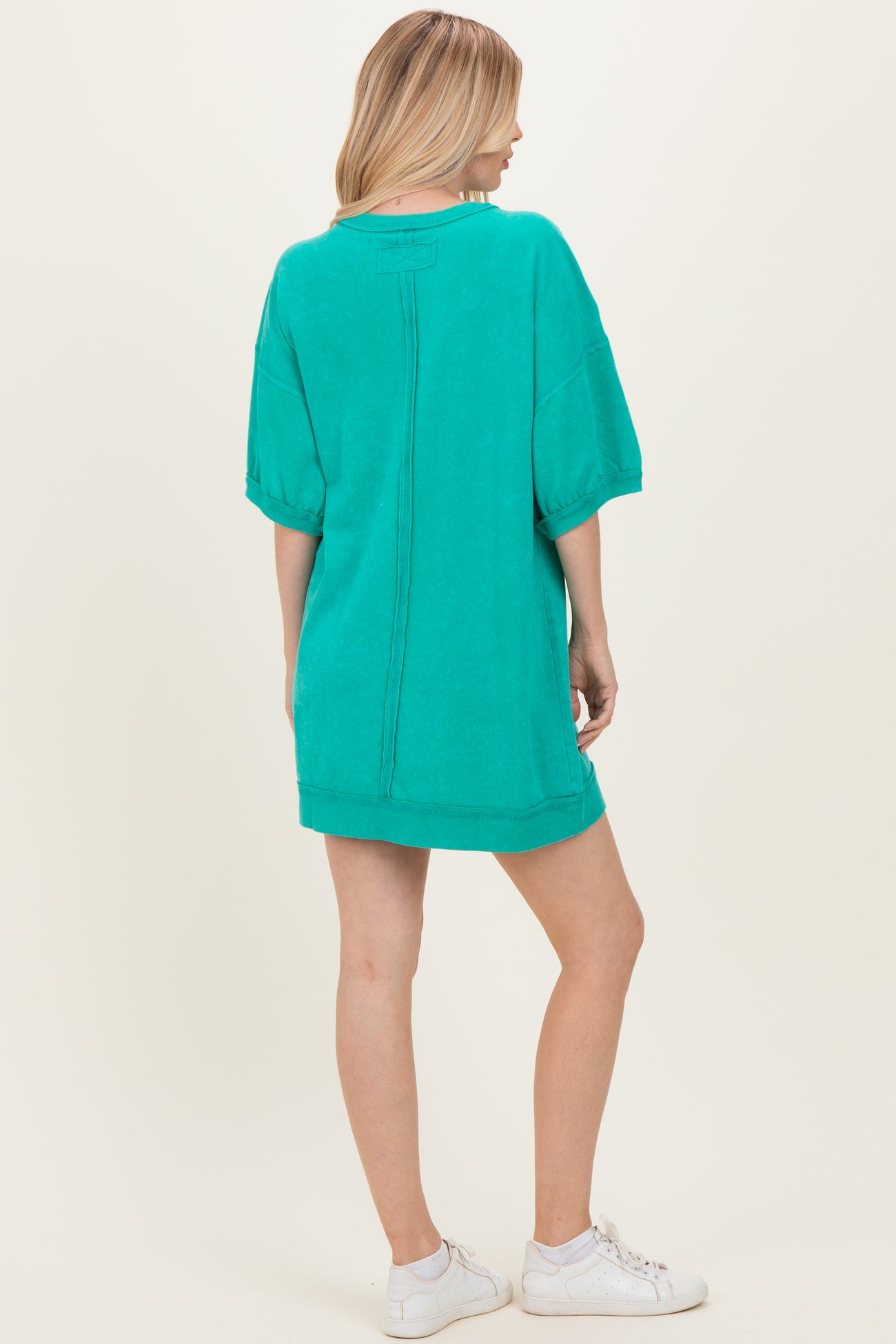 woman wearing a green oversized pullover dress with short sleeves and a relaxed fit, shown from the back