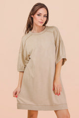woman wearing a loose-fitting beige oversized t-shirt dress with short sleeves