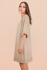woman wearing a beige oversized t-shirt dress with short sleeves and a relaxed fit