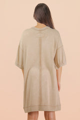 woman wearing a beige oversized sweatshirt dress with a simple back design and short sleeves