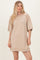 woman wearing a beige oversized short sleeve dress with a relaxed fit and ribbed details