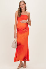 woman wearing a strapless orange maternity dress with floral print and holding her baby bump