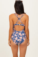 woman wearing a floral print one-piece swimsuit with crisscross straps and an open back