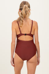 woman wearing a burgundy maternity swimsuit with a back cutout and adjustable straps, showing no visible baby bump