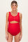 woman wearing a red maternity swimsuit with scalloped edges and a front cut-out, showcasing her baby bump