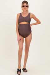 woman wearing a brown maternity swimsuit with scalloped edges and button details, showing her baby bump