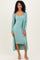 woman wearing a mint green ribbed midi dress with a matching long cardigan and strappy heels