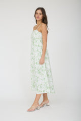 woman wearing a floral green and white maxi dress with spaghetti straps and strappy sandals