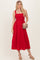 woman wearing a red sleeveless midi dress with a square neckline and a flowy hem, holding a small handbag