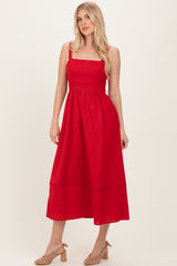 woman wearing a red midi dress with spaghetti straps and a cinched waist, styled with neutral block-heeled shoes