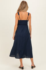 woman wearing a navy blue maternity dress with a smocked bodice and tiered hem, shown from the back