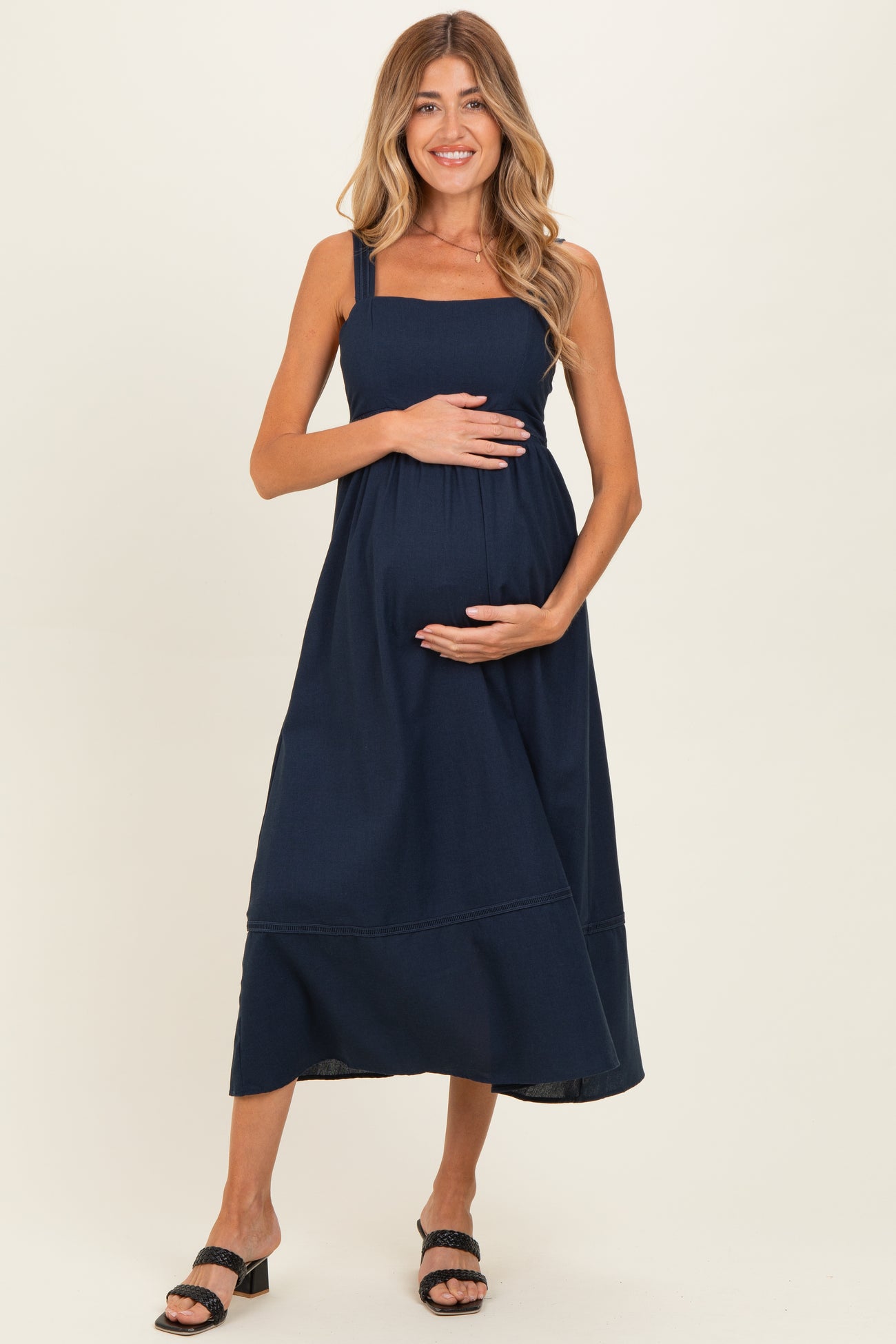 woman wearing a navy blue maternity dress with adjustable straps and a visible baby bump