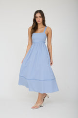 woman wearing a light blue midi dress with adjustable straps and a tiered hemline
