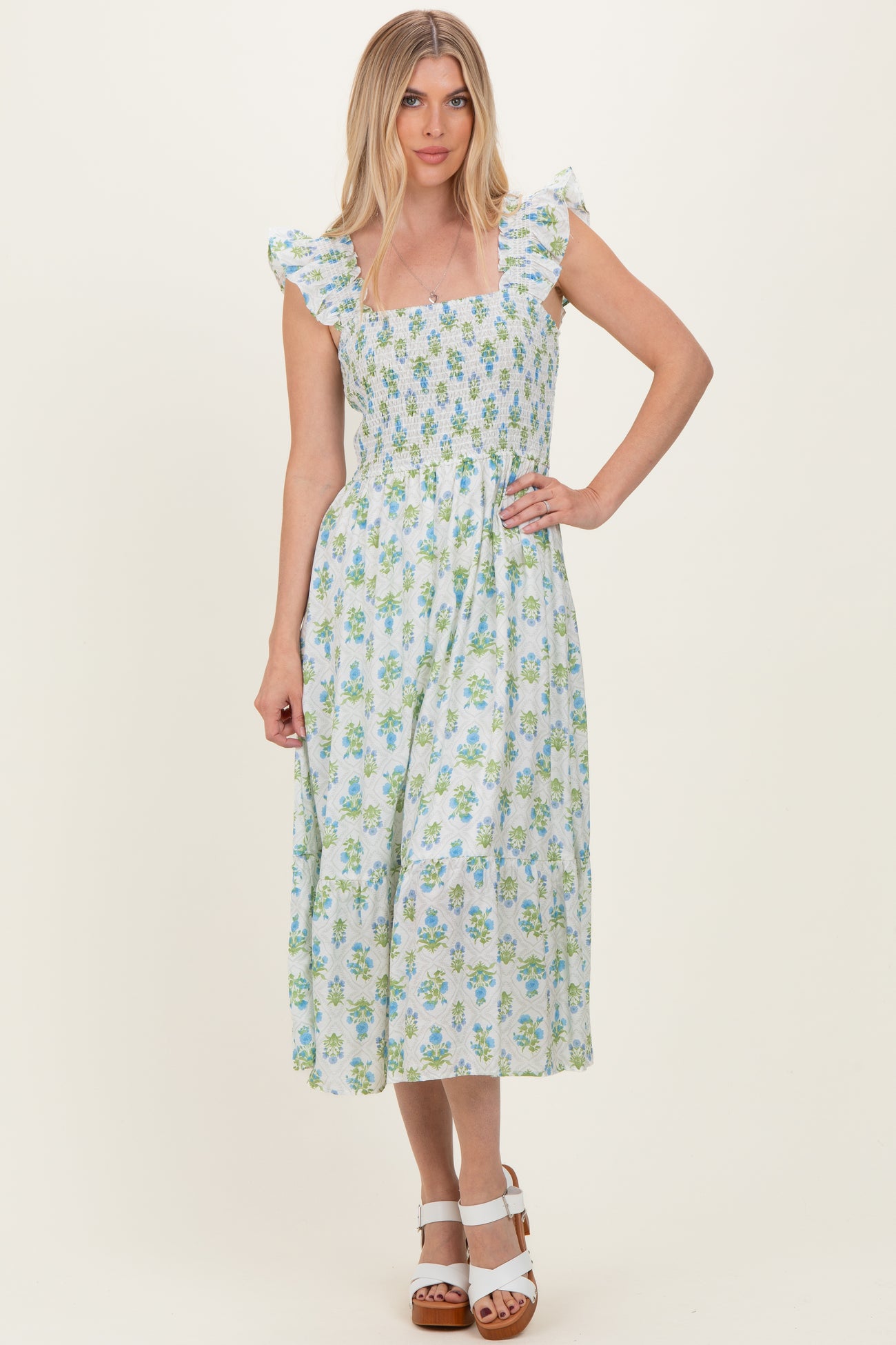 woman wearing a floral print midi dress with ruffle sleeves and smocked bodice