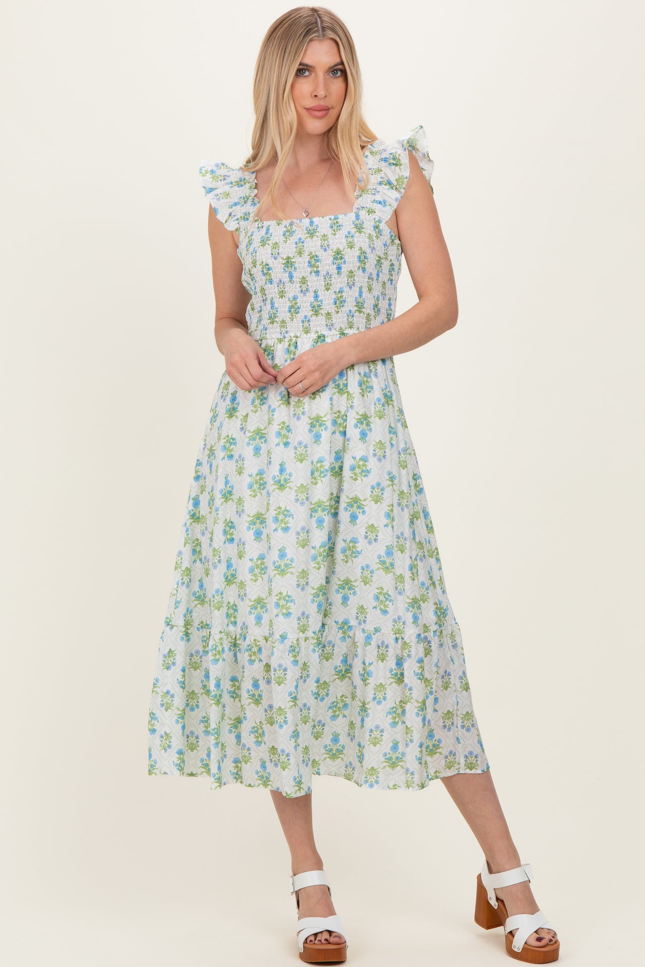 woman wearing a square neckline floral midi dress with ruffle straps in light blue and green colors