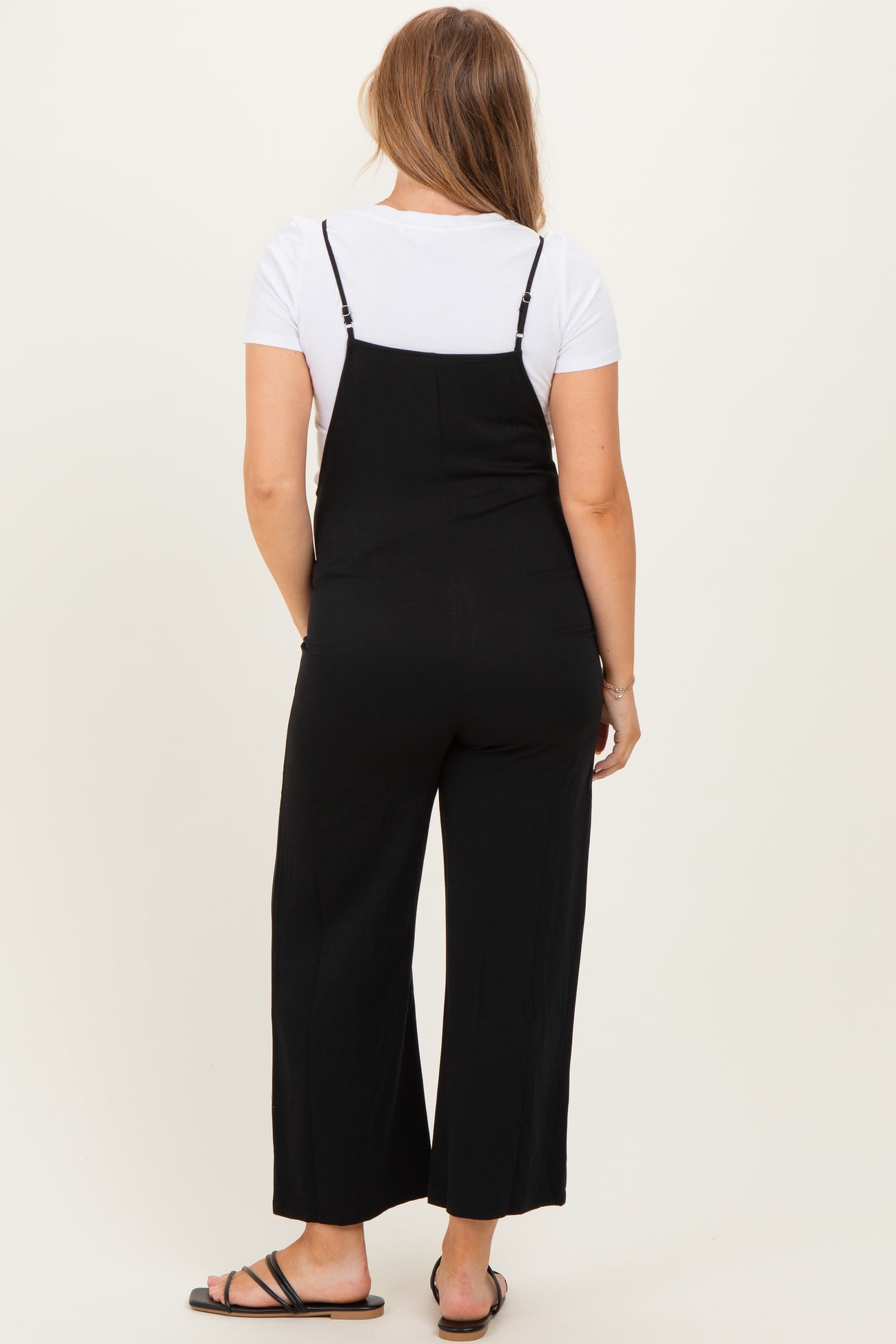 woman wearing a black maternity jumpsuit with wide legs, showing a relaxed fit from the back
