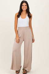 woman wearing a white sleeveless top and beige wide-leg pants with a smocked waist