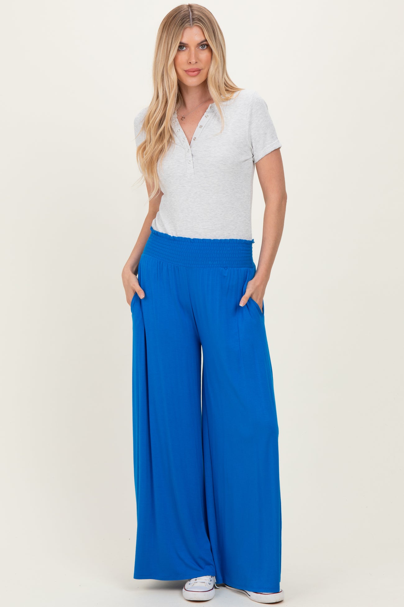 woman wearing a light gray short sleeve henley top and bright blue wide-leg pants with pockets