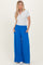 woman wearing a light gray short sleeve henley top and bright blue wide-leg pants with pockets